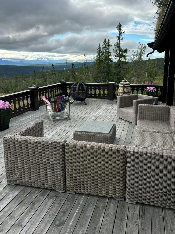 A deck with wicker furniture, a telescope, and a view of mountains. - Mountain cabin by Femunden facing Sølen (Engerdal)