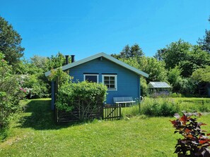 A small blue house with a wooden fence, a bench, and a garden. - Blue cottage on idyllic Askø (Maribo)