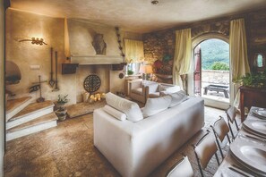 A cozy living room with a sofa, dining table, and chairs, a fireplace, and a view of the outdoors. - Medieval tower in Sibillini Mountains Park (Montefortino FM)