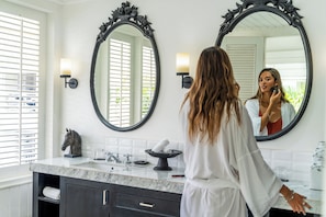 A bathroom with two large mirrors, a horse sculpture, a towel rack, and a marble countertop. - White Horse Retreat  (Lembongan Island)