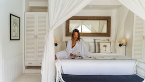 Una habitación con cama, armario blanco, espejo y un cuadro en la pared.