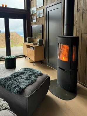 A modern living room with a wood-burning stove, a television, and a view of the outdoors. - Modern cabin with mountain views in Rauland (Rauland)