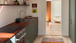 A kitchen with a wooden countertop, a sink, and a stove. There is a colorful striped rug on the floor. - Elegant summer house close to the beach and forest (Kalundborg)