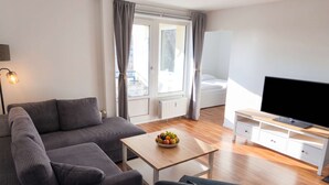 A modern living room with a sofa, a TV, and a table with fruit. - Moewennest in Rostock (Rostock)