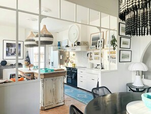 Eine moderne Küche mit weißen Schränken, ein Essbereich mit einem runden Tisch und ein großes Fenster mit Blick.