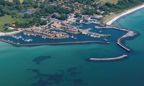 An aerial view of a coastal town with a marina, houses, and a beach. - Holiday home with harbour view in Klintholm (Borre)