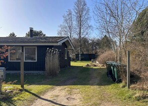 Une petite cabane avec une seule fenêtre, une porte et une cheminée.