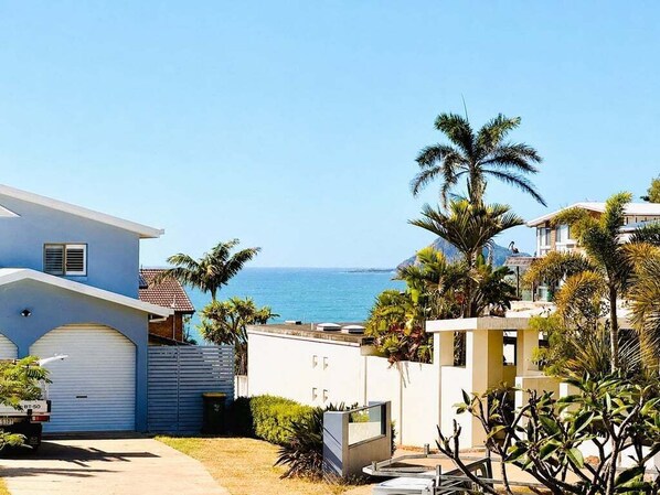 A residential area with a house, palm trees, and a view of the ocean.