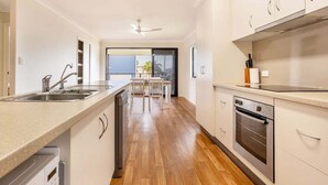 Eine moderne Küche mit Geschirrspüler, Backofen und Essbereich mit Tisch und Stühlen.