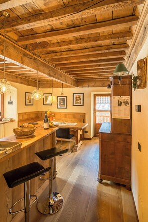 A rustic kitchen with wooden beams, a bar area with stools, and a dining table. - Mountain house with Alpine views in Traverses (Traverses)