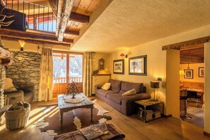 A cozy living room with a stone wall, a wooden ceiling, a brown sofa, a coffee table, and a fireplace. - Mountain house with Alpine views in Traverses (Traverses)