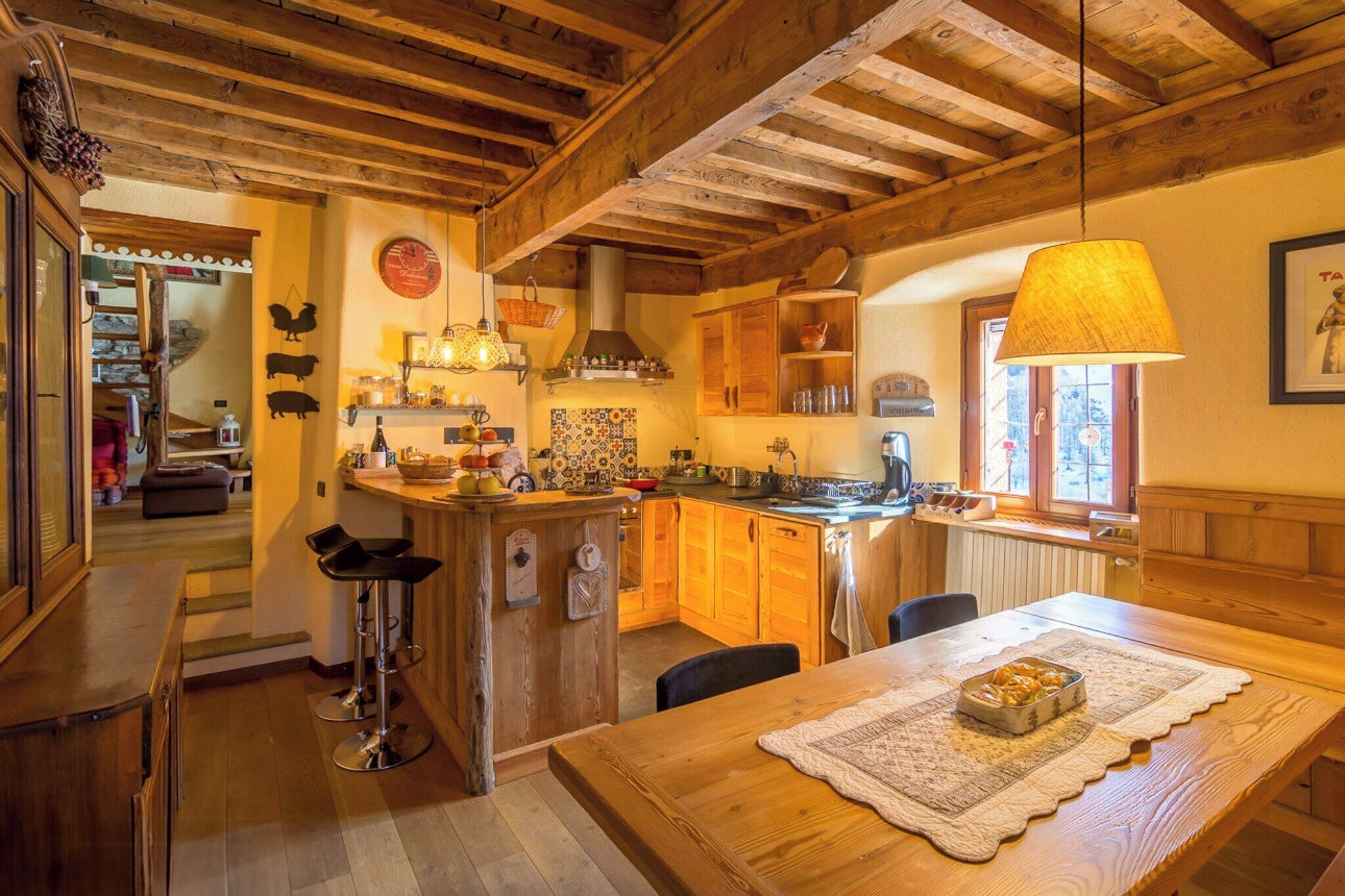 Una cocina rústica con vigas de madera, una barra y una mesa de comedor con un mantel individual.