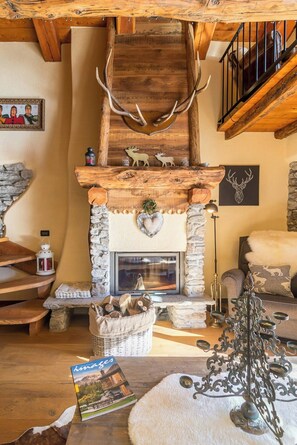 A rustic interior with a stone fireplace, wooden beams, antlers, and a cozy seating area. - Mountain house with Alpine views in Traverses (Traverses)