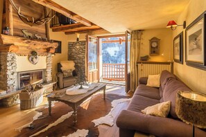 A cozy living room with a fireplace, a sofa, a coffee table, and a view of the outdoors. - Mountain house with Alpine views in Traverses (Traverses)