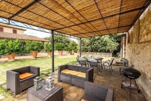 An outdoor patio with wicker furniture, a grill, and potted plants. - Restored barn with views of Siena countryside (Castelnuovo Berardenga)