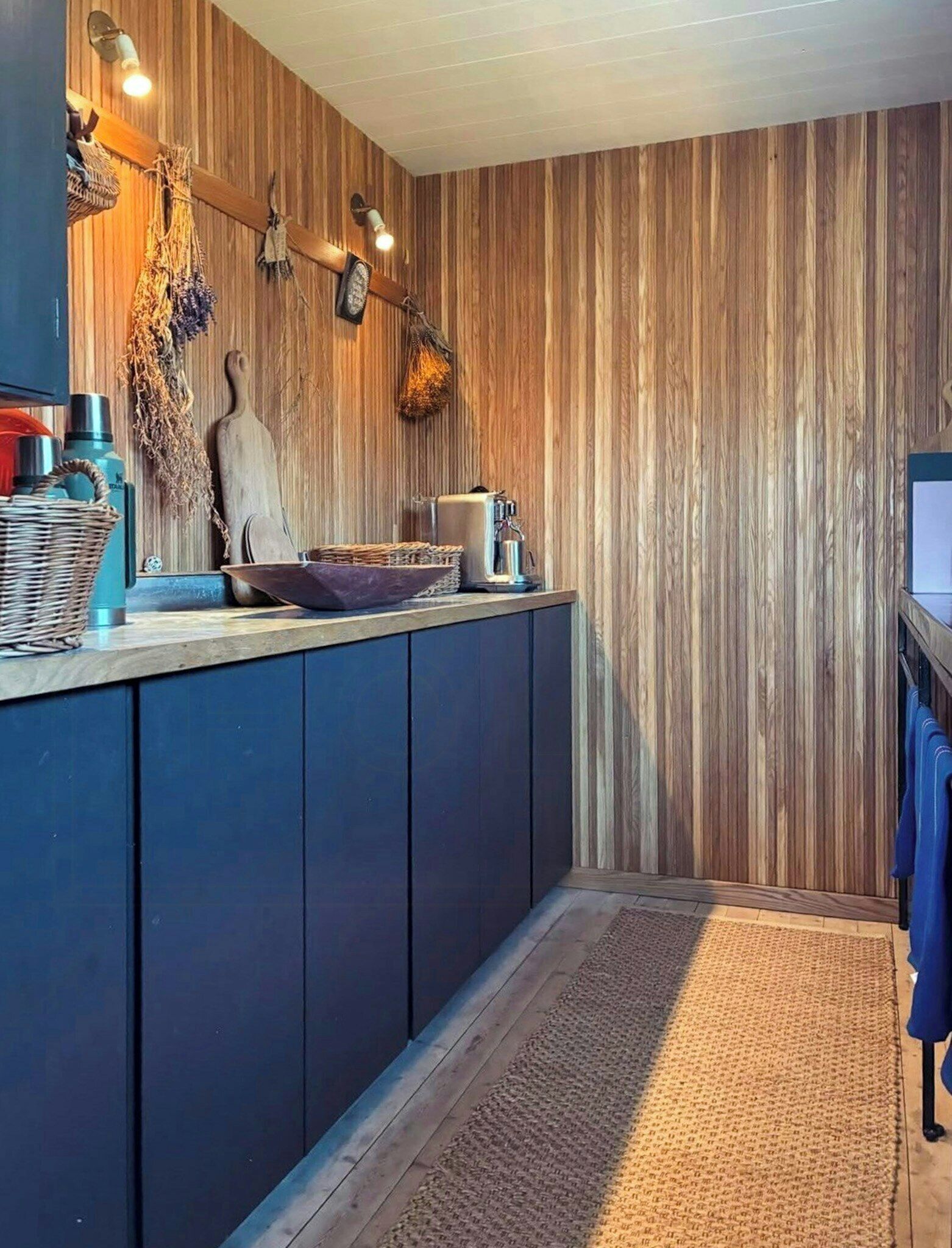 Una cocina con paneles de madera, una cafetera y una lámpara colgante.