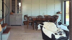 Ein geräumiger Raum mit Esstisch, Stühlen, einem Schrank und einem Fellstuhl.