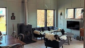 Ein geräumiges Wohnzimmer mit Kamin, einer Couch, einem Esstisch und einem Fernseher.