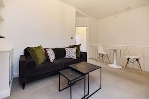 Ein modernes Wohnzimmer mit einer Couch, einem Couchtisch und einem Essbereich mit Stühlen.