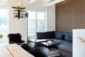 Ein modernes Wohnzimmer mit einem grauen Sofa, einem Holzesstisch und einem schwarzen Sessel.