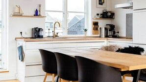 A modern kitchen with white cabinetry, a wooden countertop, and a black dining table with chairs. - Maritime atmosphere in Holiday Island (Ebeltoft)