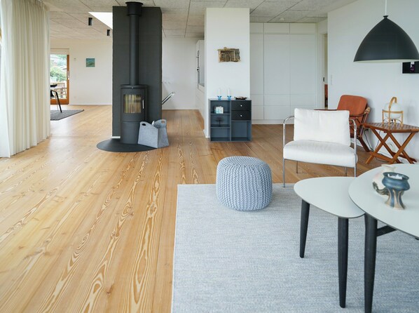 Un salon moderne avec un plancher en bois, une cheminée noire, un canapé blanc et une table ronde.