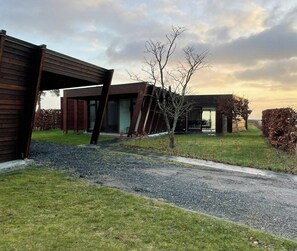 A modern building with a sloped roof, large windows, and a gravel driveway. - View over Aarhus bay from striking architecture (Egå)