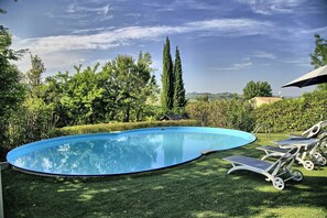 A swimming pool with a curved edge, surrounded by well-maintained grass and trees. - Villa with views of Ostra and Marche countryside (Ostra)