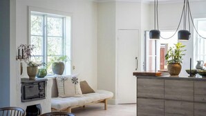 A kitchen with a wooden island, a dining area with a sofa, and a large window.