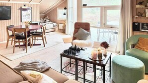 A cozy loft-style room with a loft bed, a dining area, a green armchair, and a chessboard. - House in the heather with sea view on Odden (Sjællands Odde)
