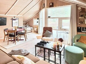 A cozy loft-style room with a loft bed, a dining area, a green armchair, and a chessboard. - House in the heather with sea view on Odden (Sjællands Odde)
