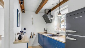 Una cocina moderna con refrigerador empotrado, vigas de madera, encimera de madera y armarios azules.