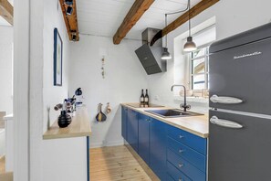 Una cocina moderna con refrigerador empotrado, vigas de madera, encimera de madera y armarios azules.