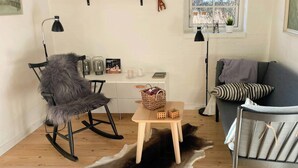 Una habitación acogedora con un sillón de piel, una mesa de madera, un sofá y una ventana con vistas.