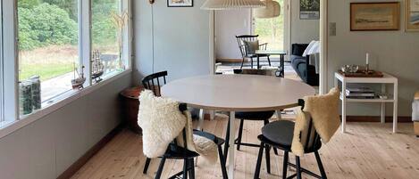 A dining area with a round table, black chairs, and a hanging light fixture.