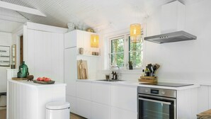 Une cuisine moderne avec des meubles blancs, un four en acier inoxydable et une fenêtre donnant sur un paysage verdoyant.