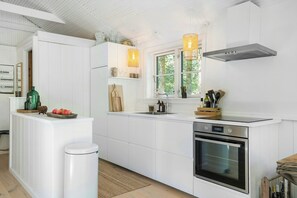 Eine moderne Küche mit weißen Schränken, einem Edelstahlbackofen und einem Fenster mit Blick auf Grünflächen.