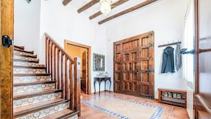 Una escalera con baldosas estampadas, una puerta de madera y un perchero con chaquetas.