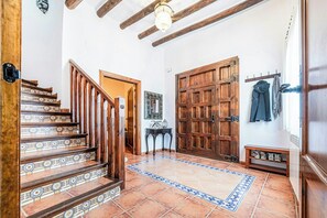 Una scala con piastrelle decorate, una porta in legno e un appendiabiti con giacche.
