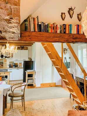 Ein rustikales Interieur mit einer Holztreppe, einer Küchenzeile und einem Bücherregal voller Bücher.