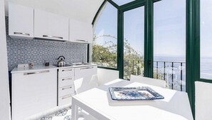 A modern kitchen with white cabinets, a patterned backsplash, and a dining area with a table and chairs.