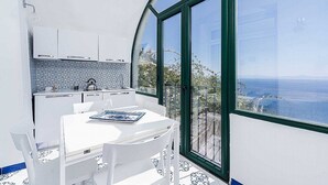 A modern kitchen with white cabinets and a view of the sea through large windows.