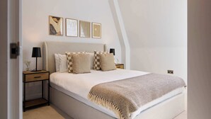 Ein Schlafzimmer mit einem großen Bett, einem Nachttisch mit Lampe und drei gerahmten Kunstwerken an der Wand.