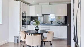 Eine moderne Küche mit weißen Schränken, einem Esstisch mit Stühlen und einer Vase mit Blumen.