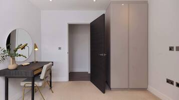 A modern room with a desk, chair, mirror, and wardrobe.