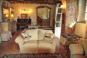 Ein gemütliches Wohnzimmer mit einer Couch, einem Esstisch und einer Treppe, die in eine obere Etage führt.