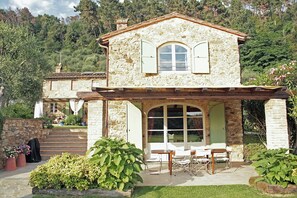 Ein Steinhaus mit Terrasse, Sitzgelegenheiten im Freien und einem Garten.
