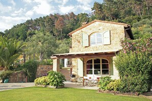 Ein Steinhaus mit Terrasse, Essbereich und Blick auf den umliegenden Wald.