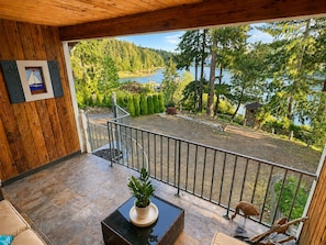 A wooden balcony with a view of a lake, a potted plant, and a framed picture on the wall.
