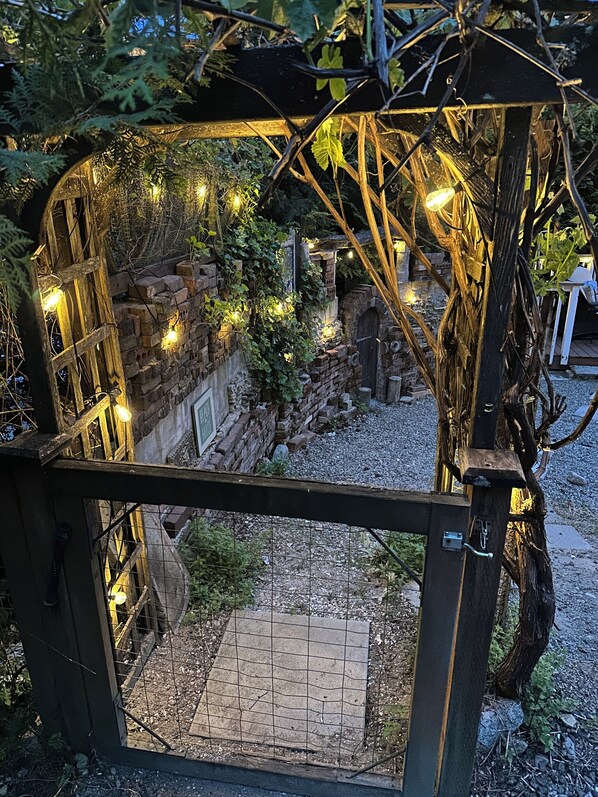 A rustic wooden structure with a brick wall, vines, and string lights.